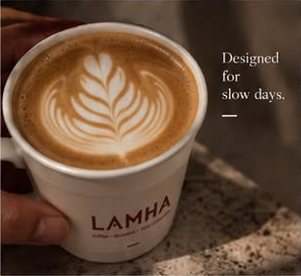 Latte with a leaf pattern in the foam, held in a LAMHA cup